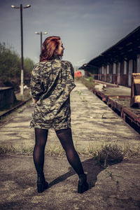 Rear view full length of young woman standing on footpath