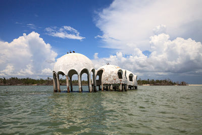 Built structure in river against cloudy sky