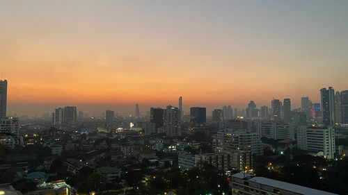 Modern buildings in city against sky during sunset