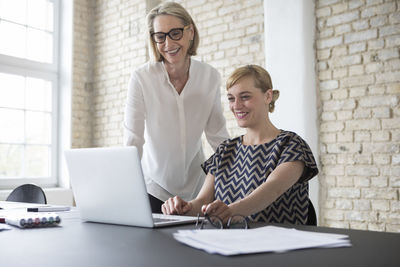 Mature businesswoman working with younger colleague in office