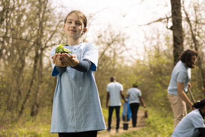 Portrait of young woman holding map while standing in park