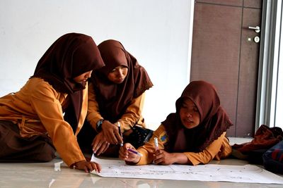 Muslim girls making project on floor