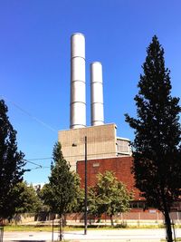 Low angle view of factory against clear blue sky