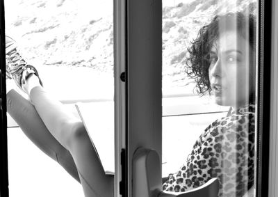 Low section of woman looking through window