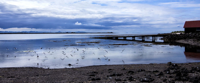 Bridge over river against cloudy sky