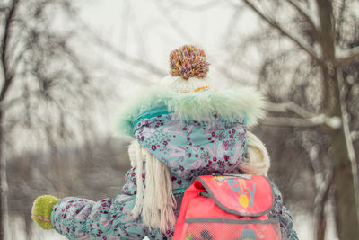 Rear view of woman standing by plants during winter