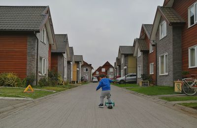 Man riding motorcycle on road amidst buildings against sky