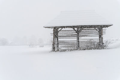 Metallic structure on snow covered field against sky