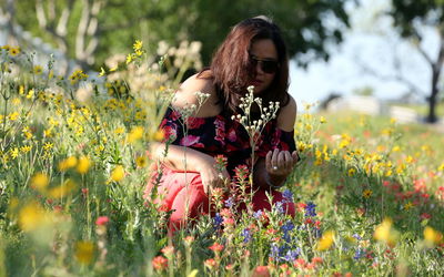 Portrait of woman in sunglasses amidst flowering plants