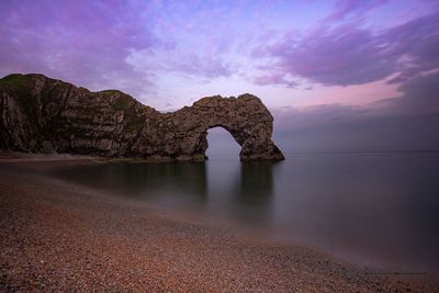 Rock formations in sea against sky during sunset