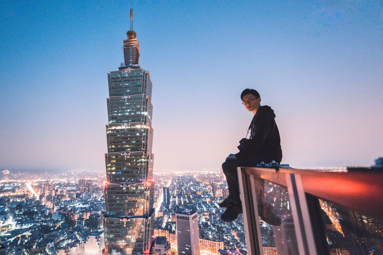 cityscape, building exterior, city, architecture, skyscraper, real people, built structure, one person, clear sky, night, outdoors, illuminated, young adult, sky, leisure activity, young women, urban skyline, portrait, modern, full length, lifestyles, looking at camera, people