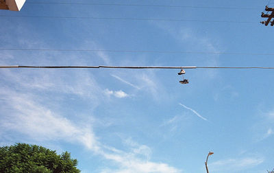 Low angle view of birds perching on cable against sky