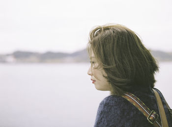 Rear view of thoughtful young woman at beach