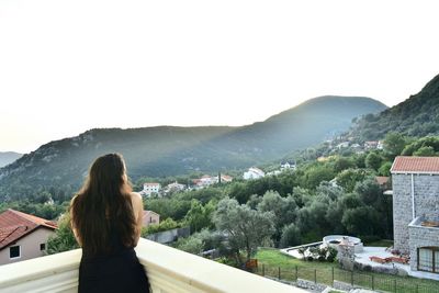 Rear view of woman looking at cityscape against sky