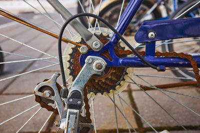 Blue bike has been outside all winter and got broken. rusty bicycle chain hangs on sprocket