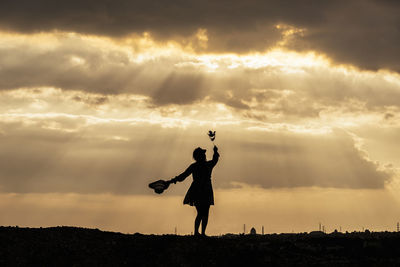 Silhouette man standing on field against sky during sunset