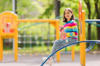 Charming  little girl, 5-6 years old, sitting with a plastic bottle of water on the playground