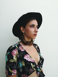 Beautiful young woman wearing fashionable clothing against wall