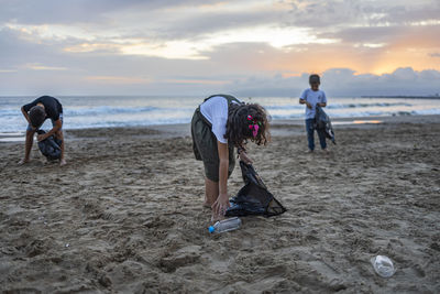 Friends collecting garbage in bags at beach