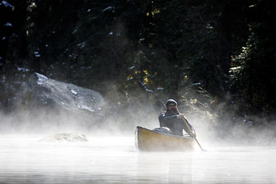 Man surfing in river against waterfall