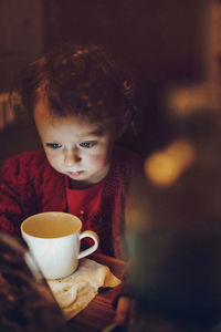 Cute girl looking at coffee in illuminated room