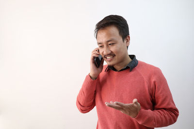 Young man using smart phone against white background