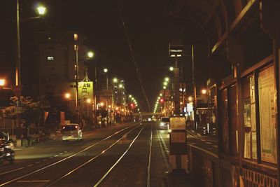 Illuminated railroad tracks in city at night