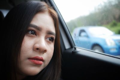 Close-up of young woman looking away in car