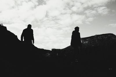 Silhouette hikers on mountain against sky