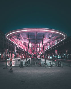 Illuminated ferris wheel in city at night