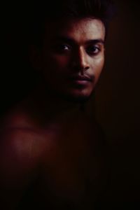 Portrait of young man against black background