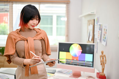 Side view of young woman using digital tablet while sitting at home