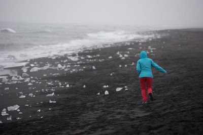 Girl running on diamond  beach,  ice blocks, jokulsarlon. atlantic ocean coast, iceland