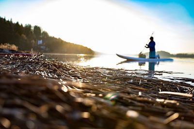 Man paddleboarding in lake against sky