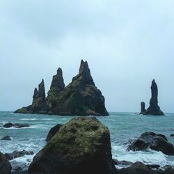 Rock formation on beach against sky