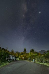 Road amidst trees against sky at night