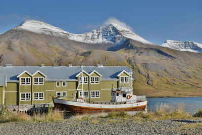 Fishing boat next to classic nordic harbor building, iceland