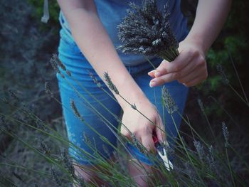 Midsection of woman holding plant on field