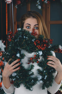 Portrait of woman holding christmas tree at home