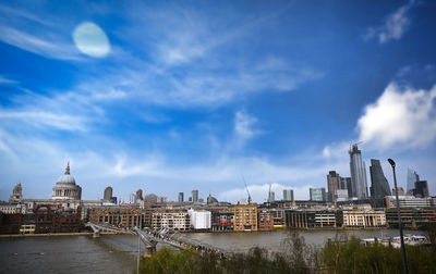 Buildings at waterfront against cloudy sky