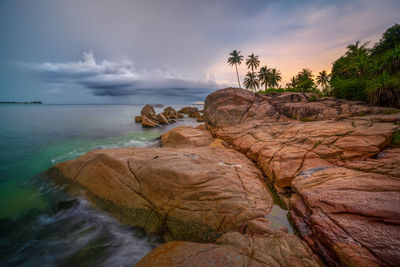 Rock formation on sea against sky during sunset