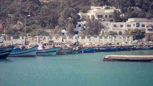 Sailboats moored on sea by buildings in city