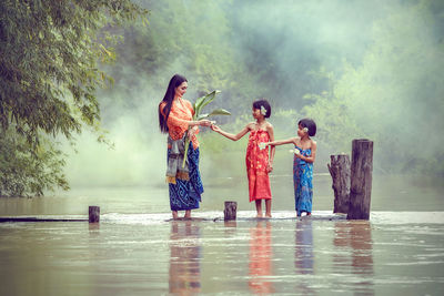 Children standing in water against sky