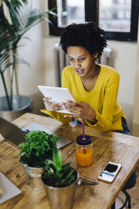 Young woman sitting at table with several portable device