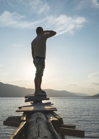Man standing on built structure over sea against sky