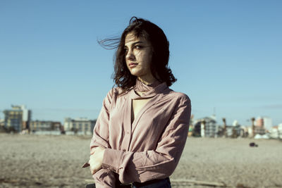 Woman standing at beach against blue sky