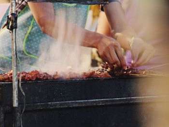 Close-up of man working on barbecue grill