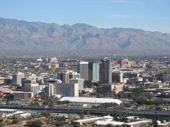 Buildings and mountains against sky on sunny day