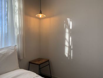 Illuminated electric lamp on bed against wall at home