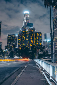 Illuminated city street and buildings against sky